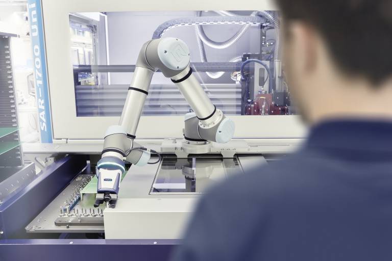 Teamwork in der Elektronikindustrie: Bei diesem Nutzentrenner unterstützt ein Roboterarm mit einem Schunk Co-act EGP-C Greifer den Bediener bei der Beladung.