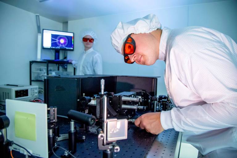 Ein Mitarbeiter von Q.ANT prüft die Qualität an einer Anlage die Licht-Leitbahnen eines photonischen Chips.
